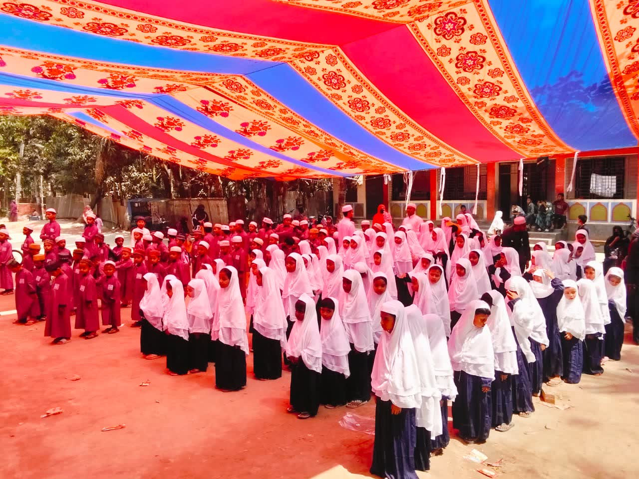 Rows of girls in pink and white hijabs standing together