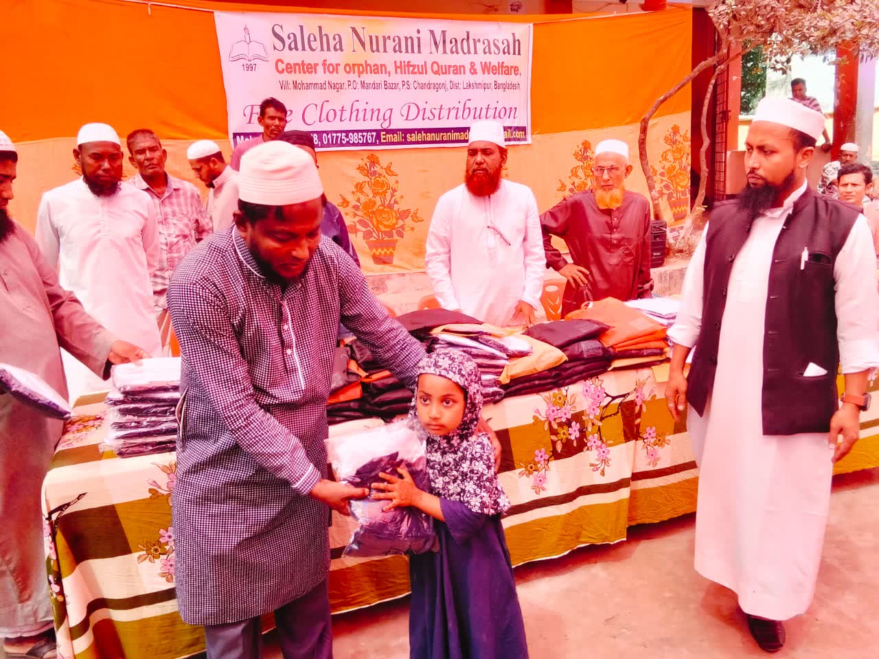 A young girl receiving a clothing package from madrasah elders