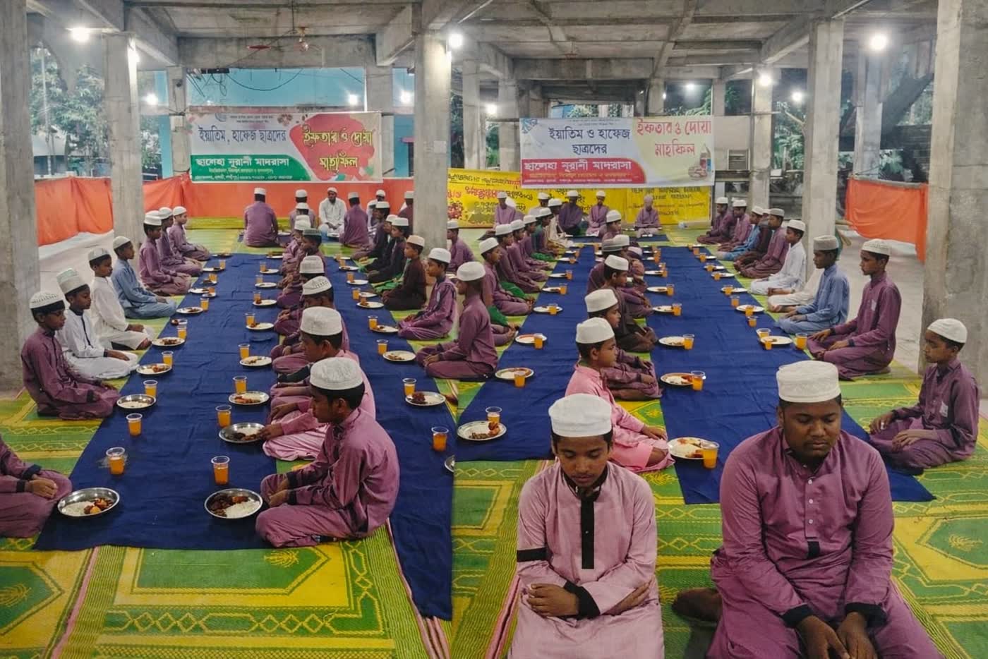 Students seated in rows for a shared meal at the madrasah